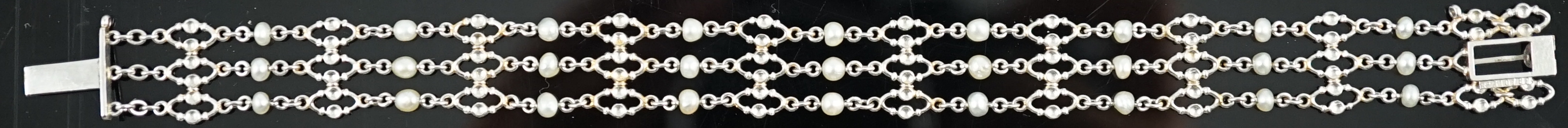 An early to mid 20th century white gold and seed pearl set three row chain link bracelet